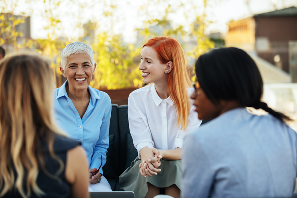 A diverse group of 4 women, seated outside, having a conversation